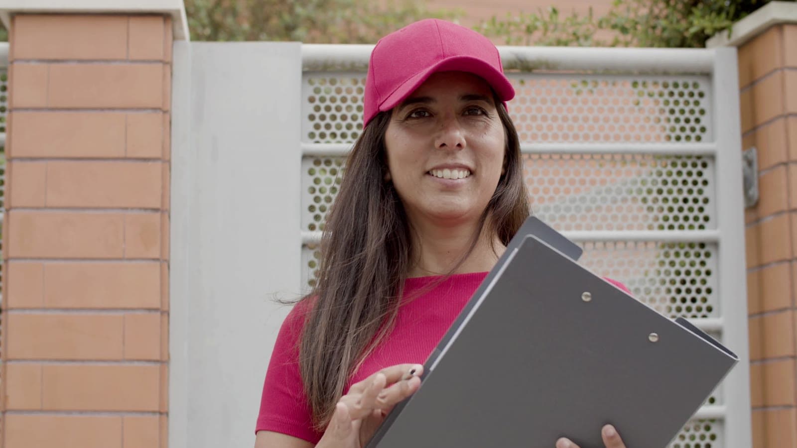 A FreightBridge Logistics delivery driver holding a clipboard at a customer’s gate